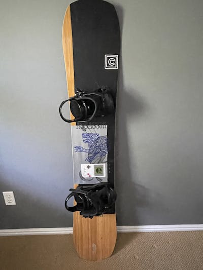 The Salomon Assassin Snowboard laying against a wall.