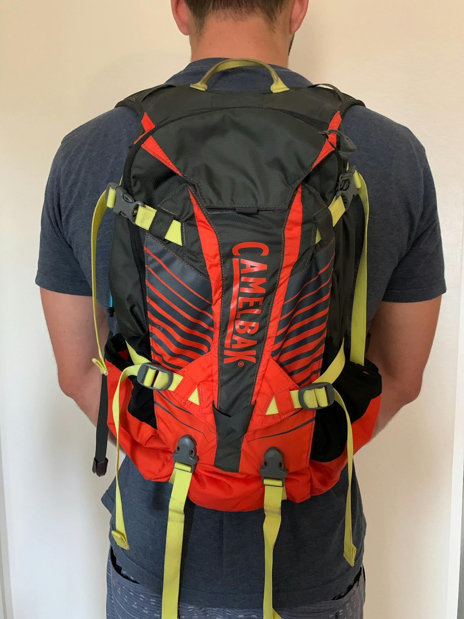 A man wears a red and black Camelbak backpack