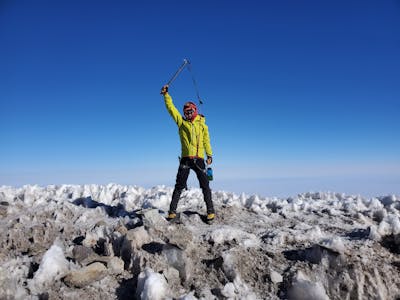 An ice climber standing at the top of a pass wearing the Rab Microlight Jacket. 