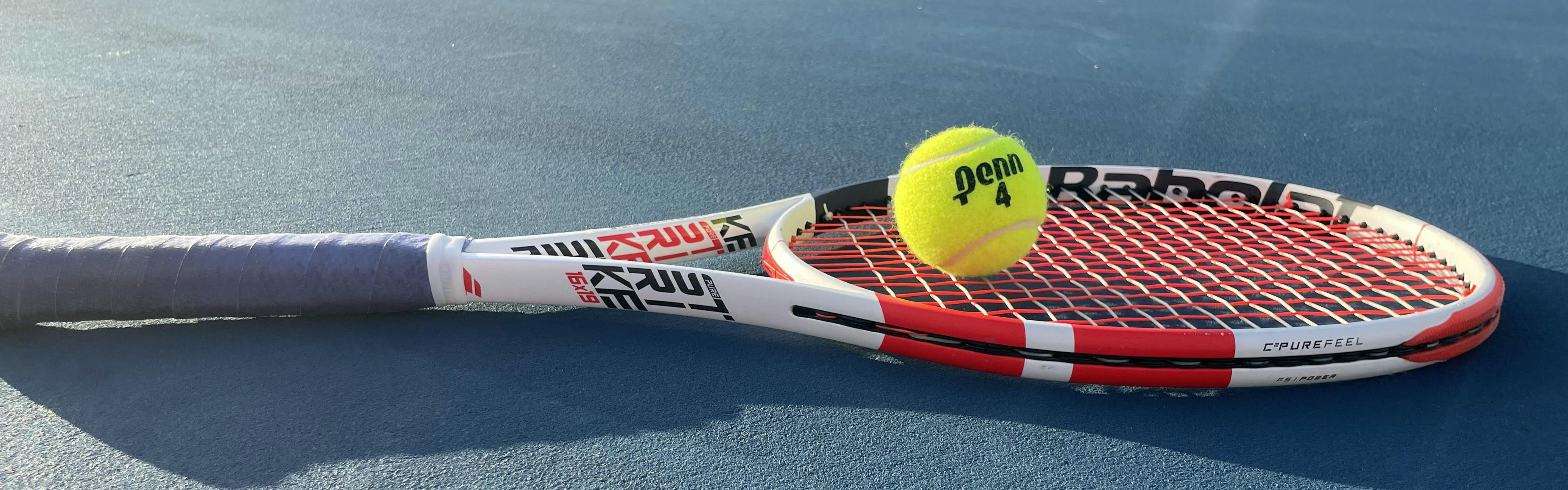 The Babolat Pure Strike 98 16x19 Racquet lying on a tennis court with a tennis ball.