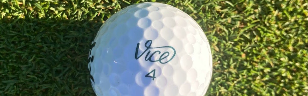 The Stix + Vice Tour Golf Ball laying in the grass.