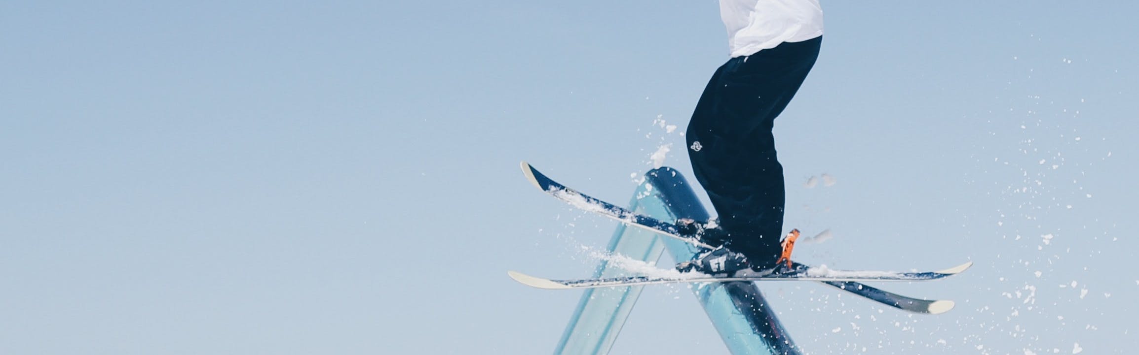 A skier slides down a rail on a blue-sky day.