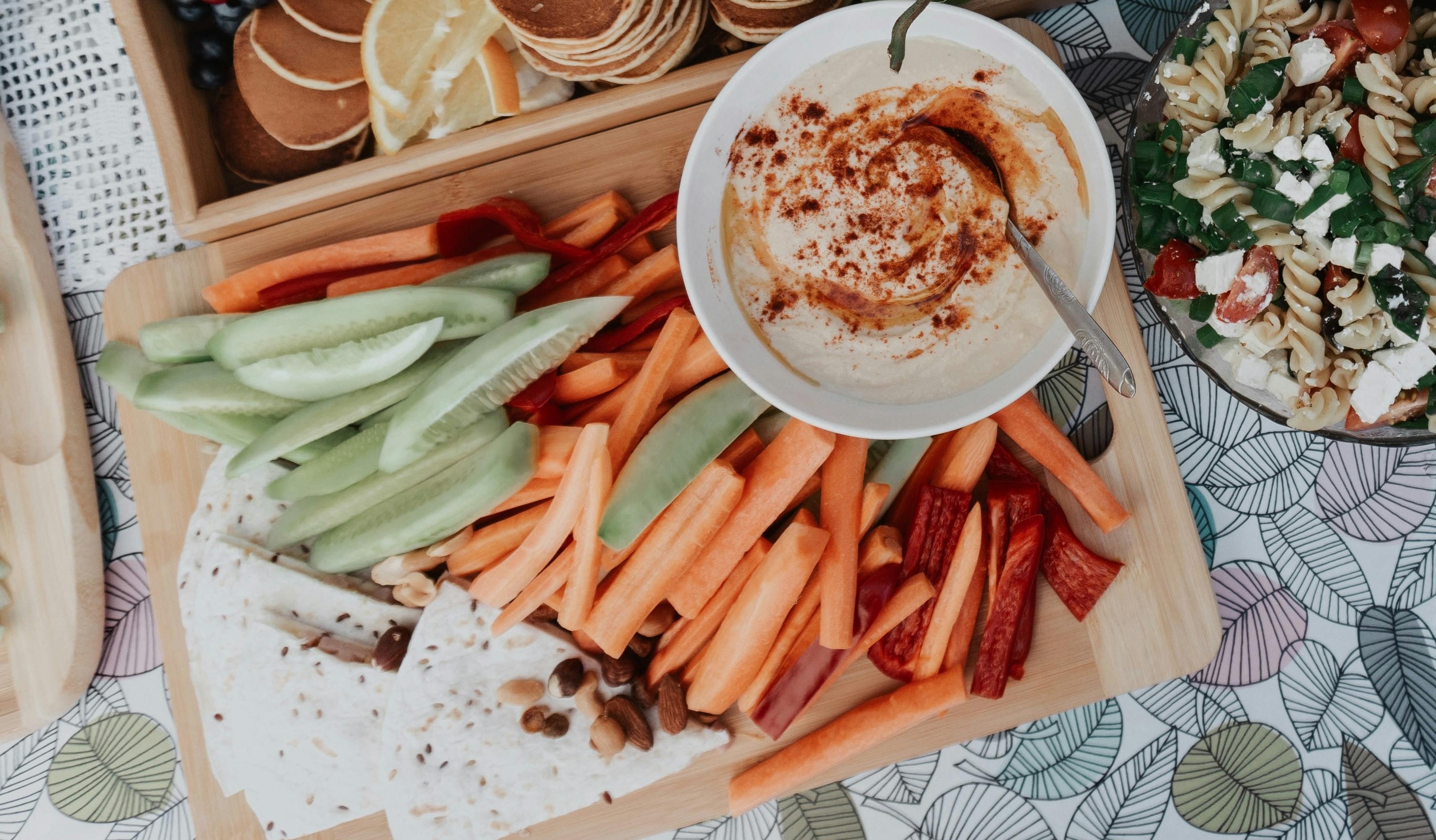 A board with carrots, celery, and hummus on it. 