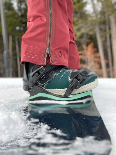 The Ride Sage boots strapped into a snowboard binding in a snowy area.