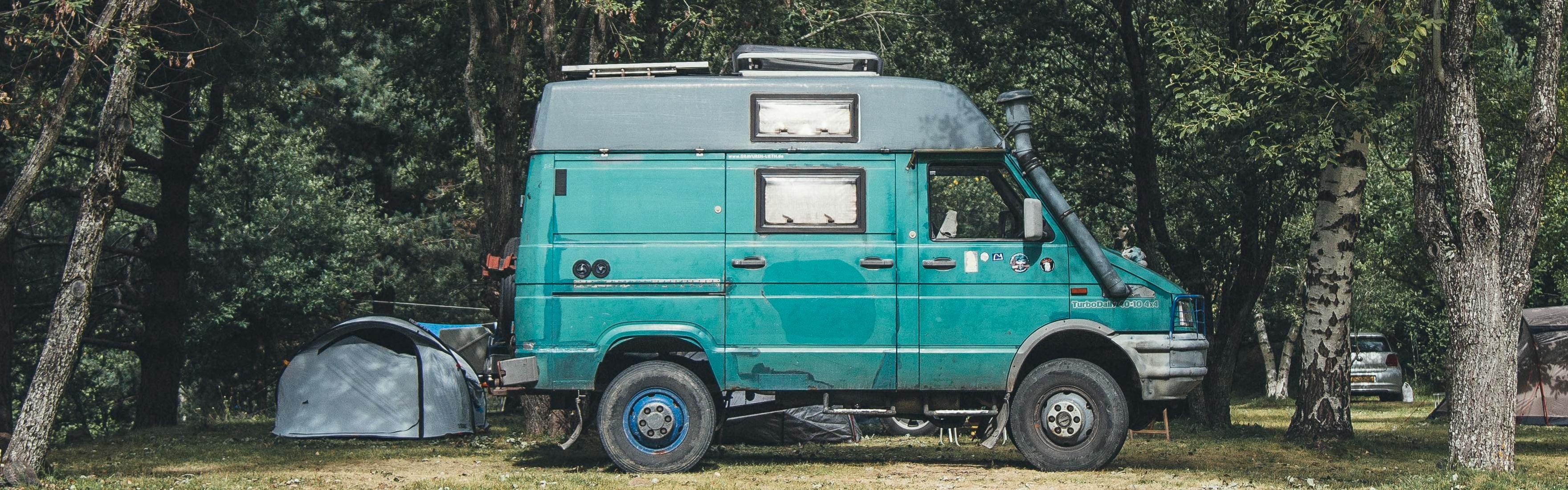 A turquoise campervan at a campsite