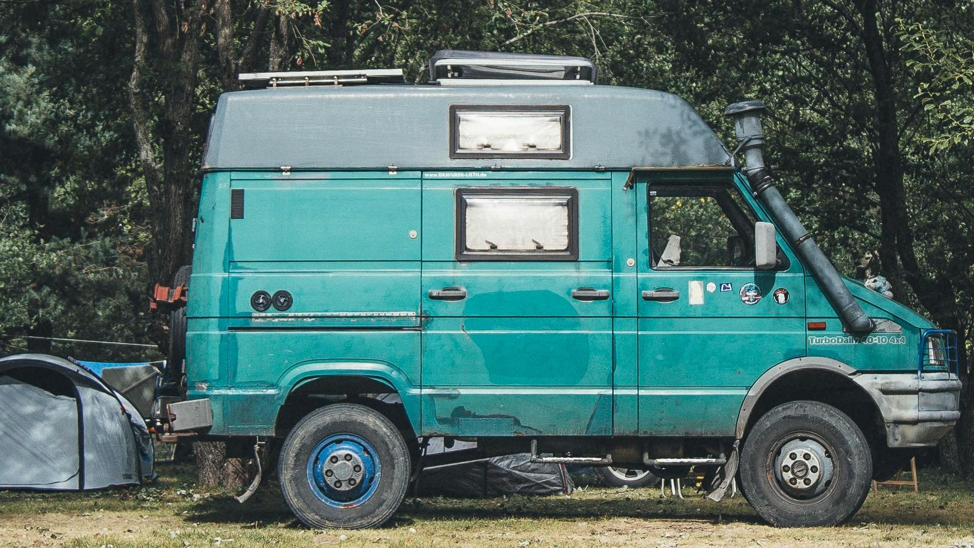 A turquoise campervan at a campsite