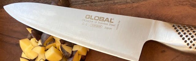 The Global Classic Chef's Knife in front of some potatoes. 