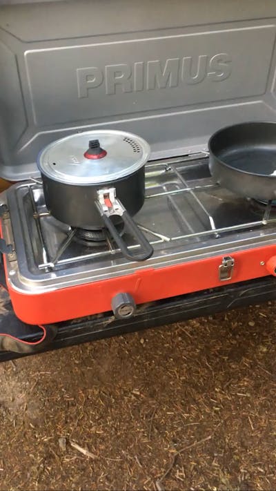 A pot and a pan on a two burner camping stove.
