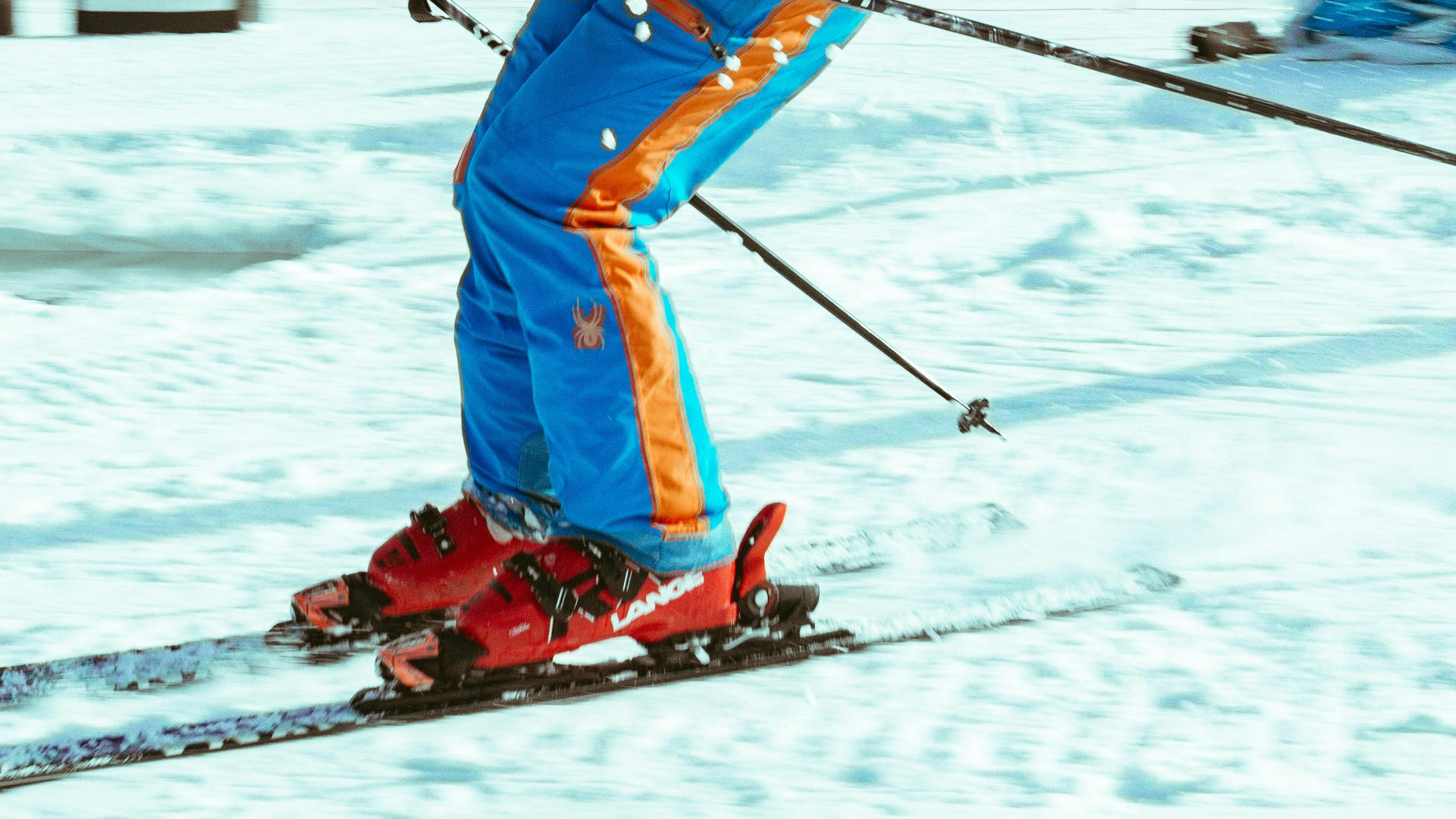 Close up of ski boots as a skier is turning down a snowy slope. 