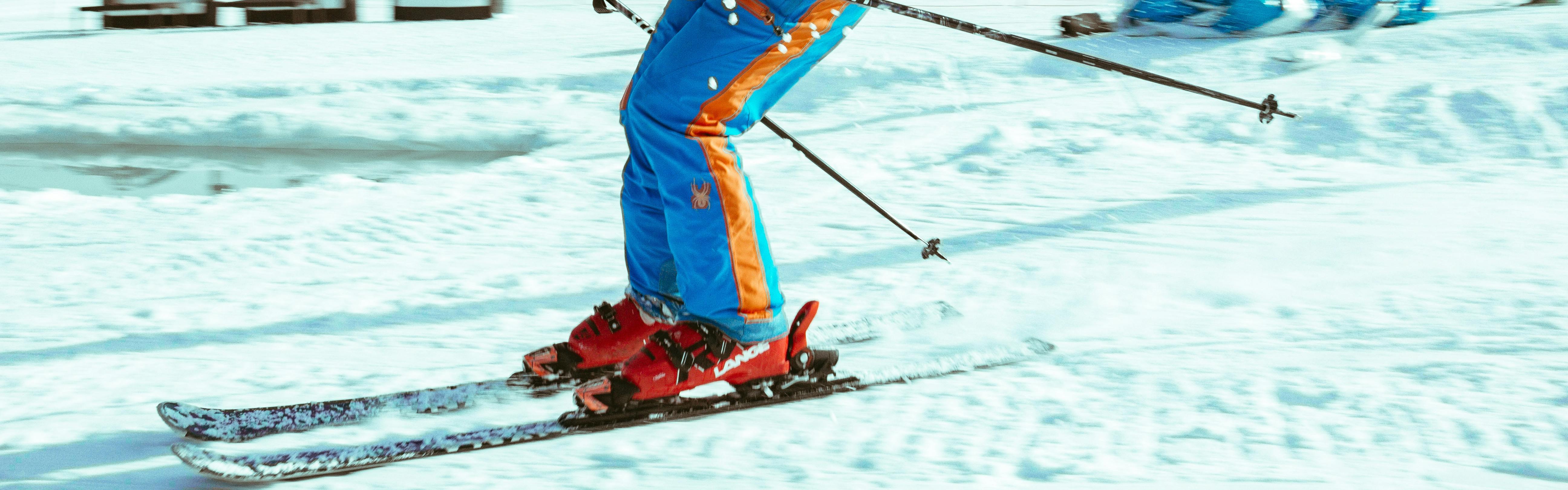 Close up of ski boots as a skier is turning down a snowy slope. 