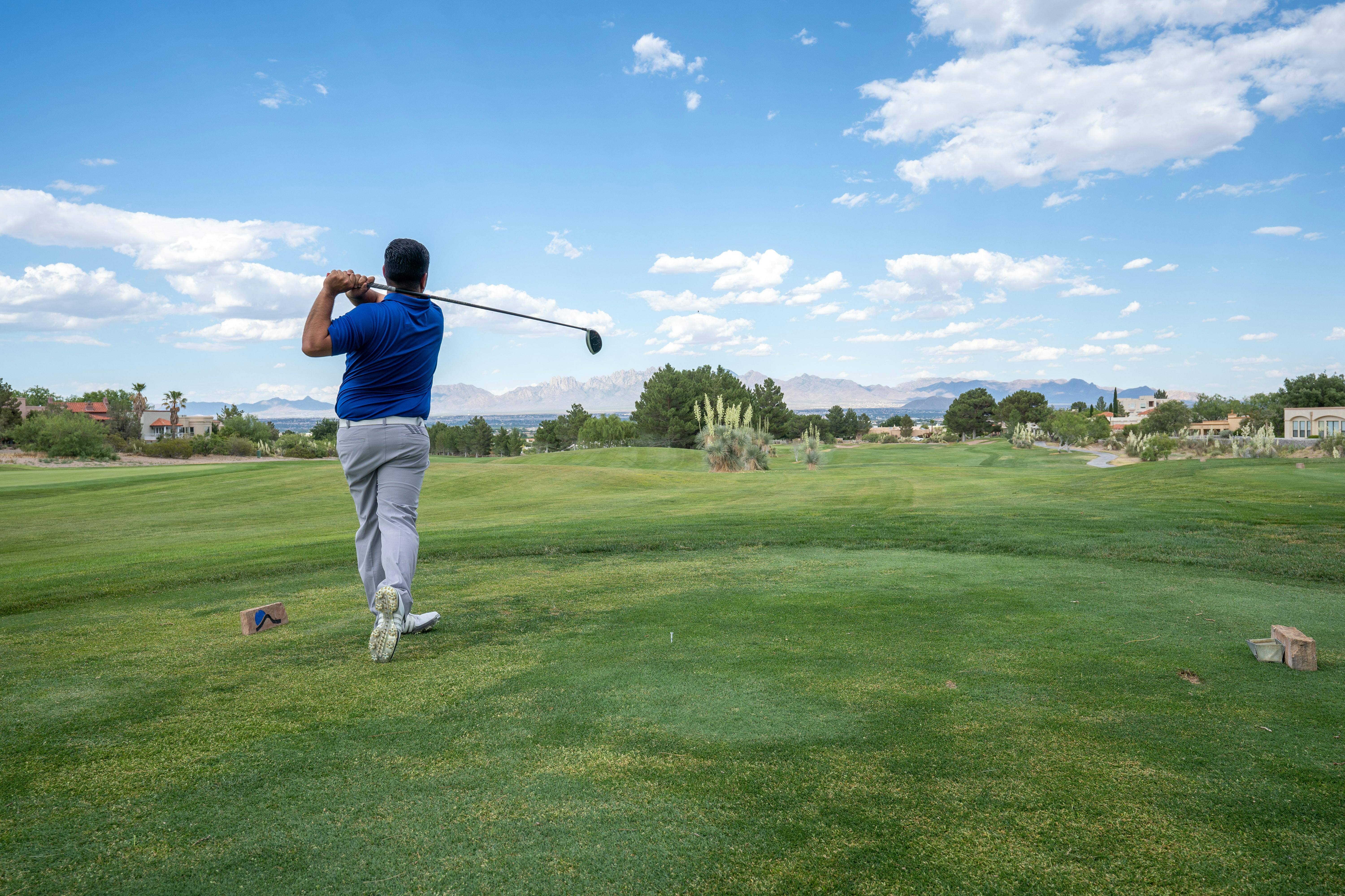 A man swings his club back on a golf course. 