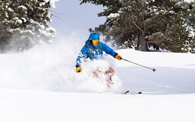 A skier makes turns through the snow wearing his POC Fornix MIPS helmet.