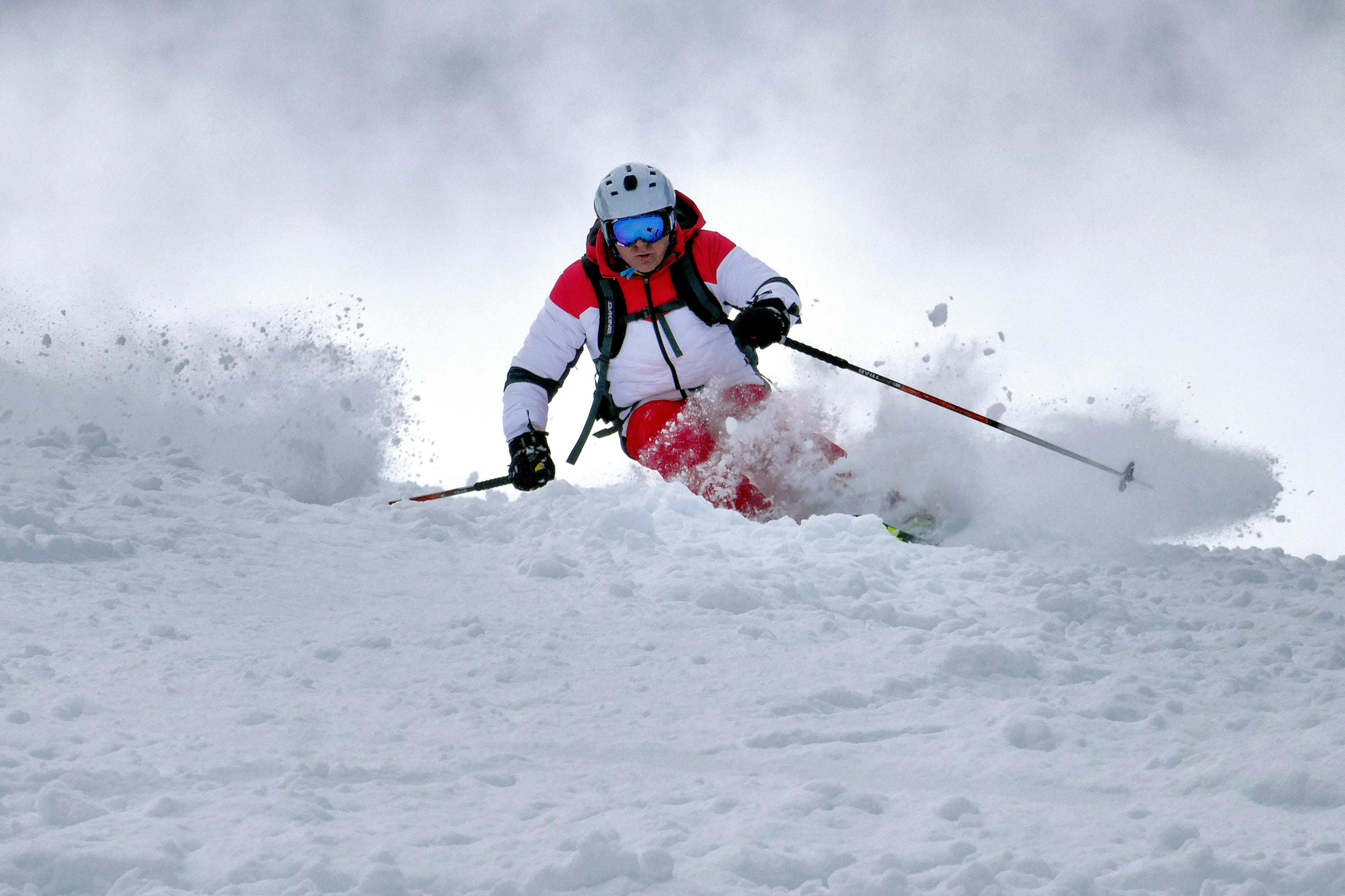 A skier in red and white executes a turn in chunky snow
