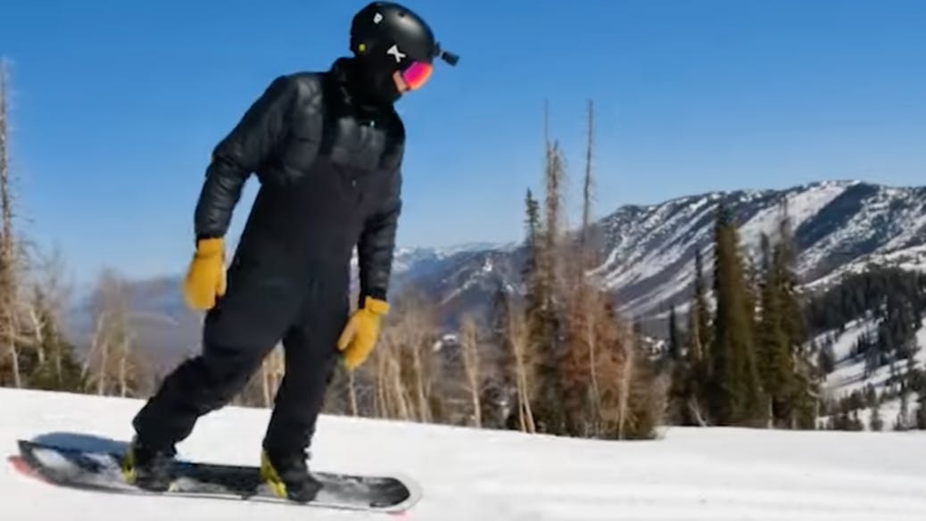 A snowboarder turning down the mountain. 