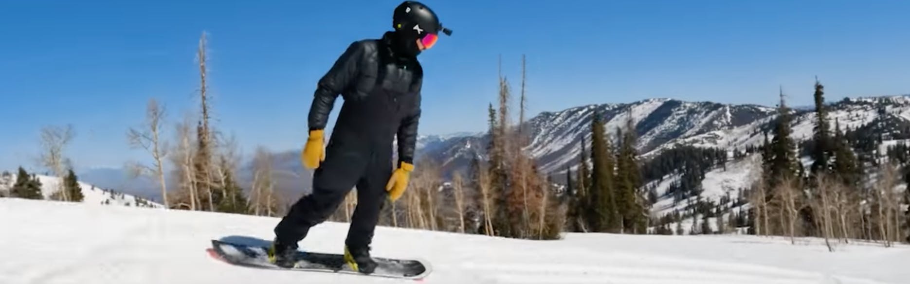 A snowboarder turning down the mountain. 