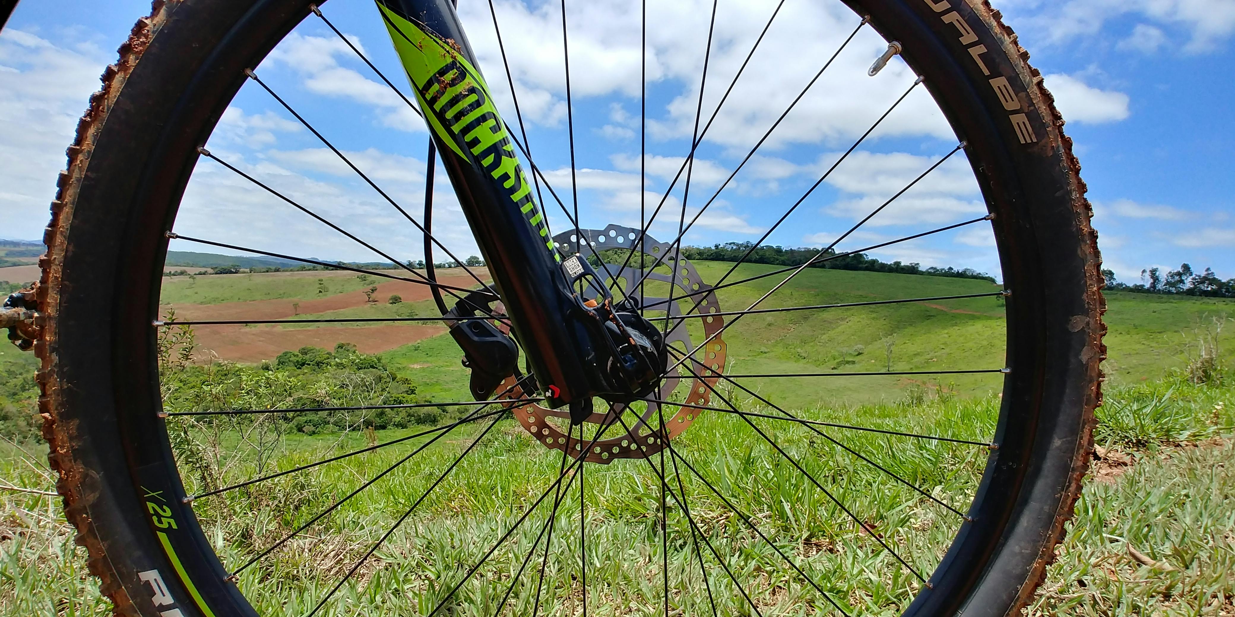 A close-up of a mountain bike tire with green rolling hills in the background. 