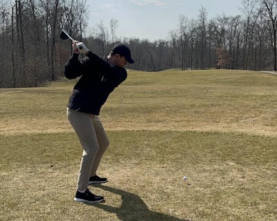 Golfer uses a driver on a driving range.