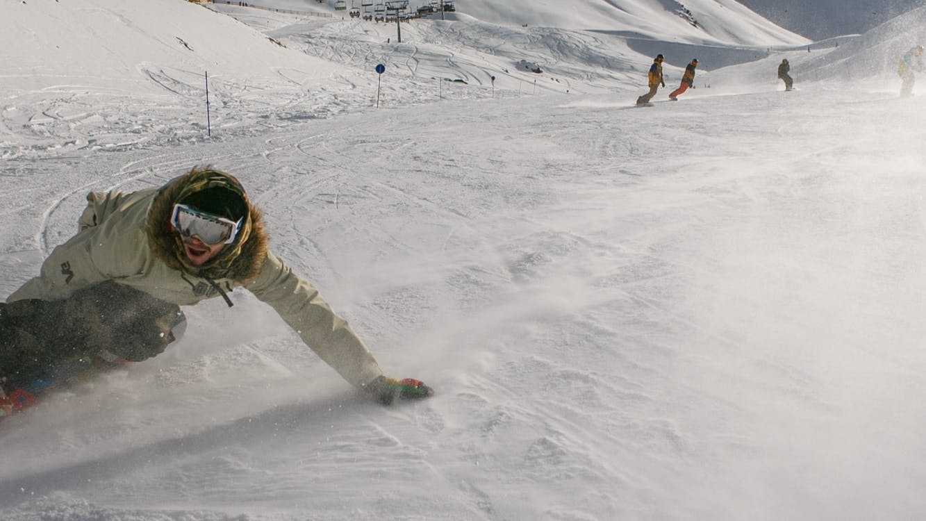 A snowboarder turns down a ski run. 