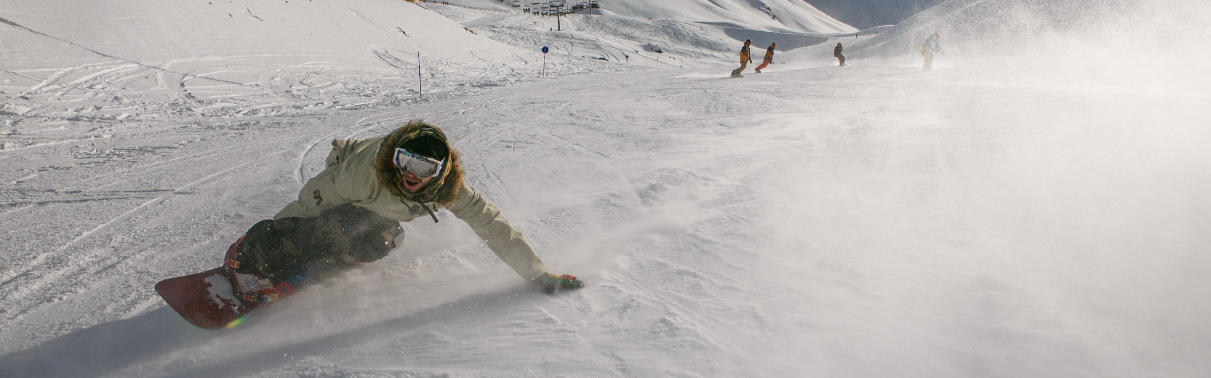 A snowboarder turns down a ski run. 