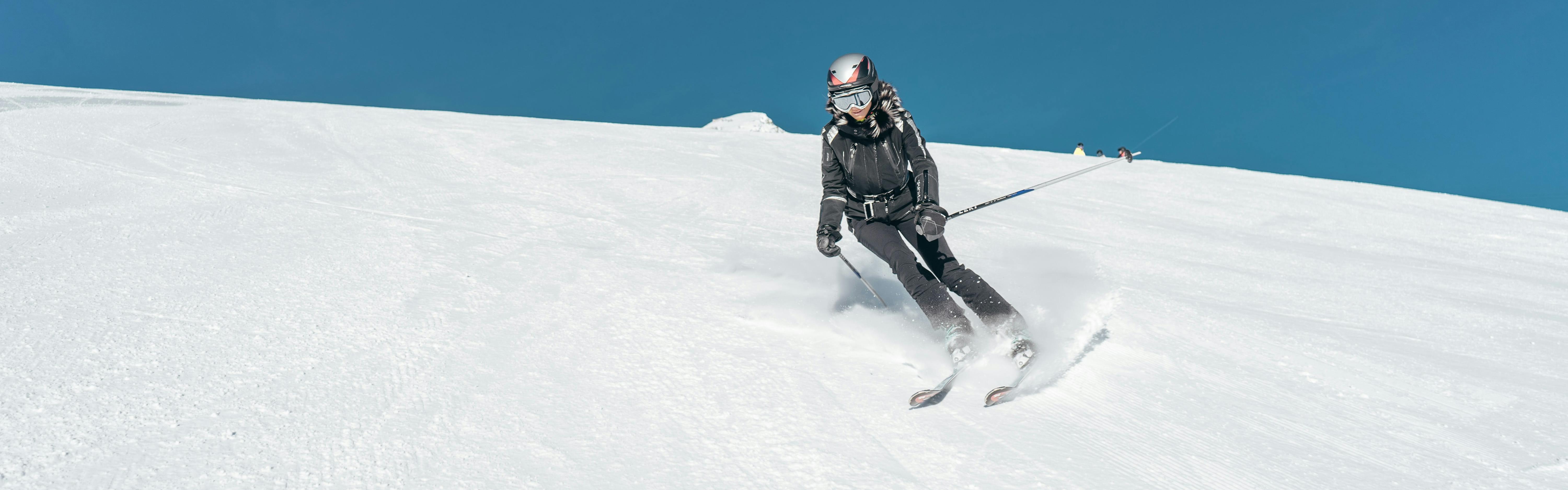 A person wearing black turns while on skis