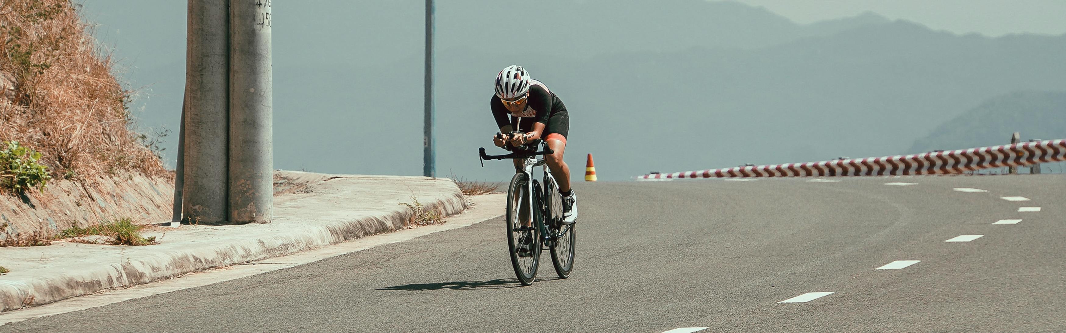 A man rides a road bike downhill with a jersey and helmet.