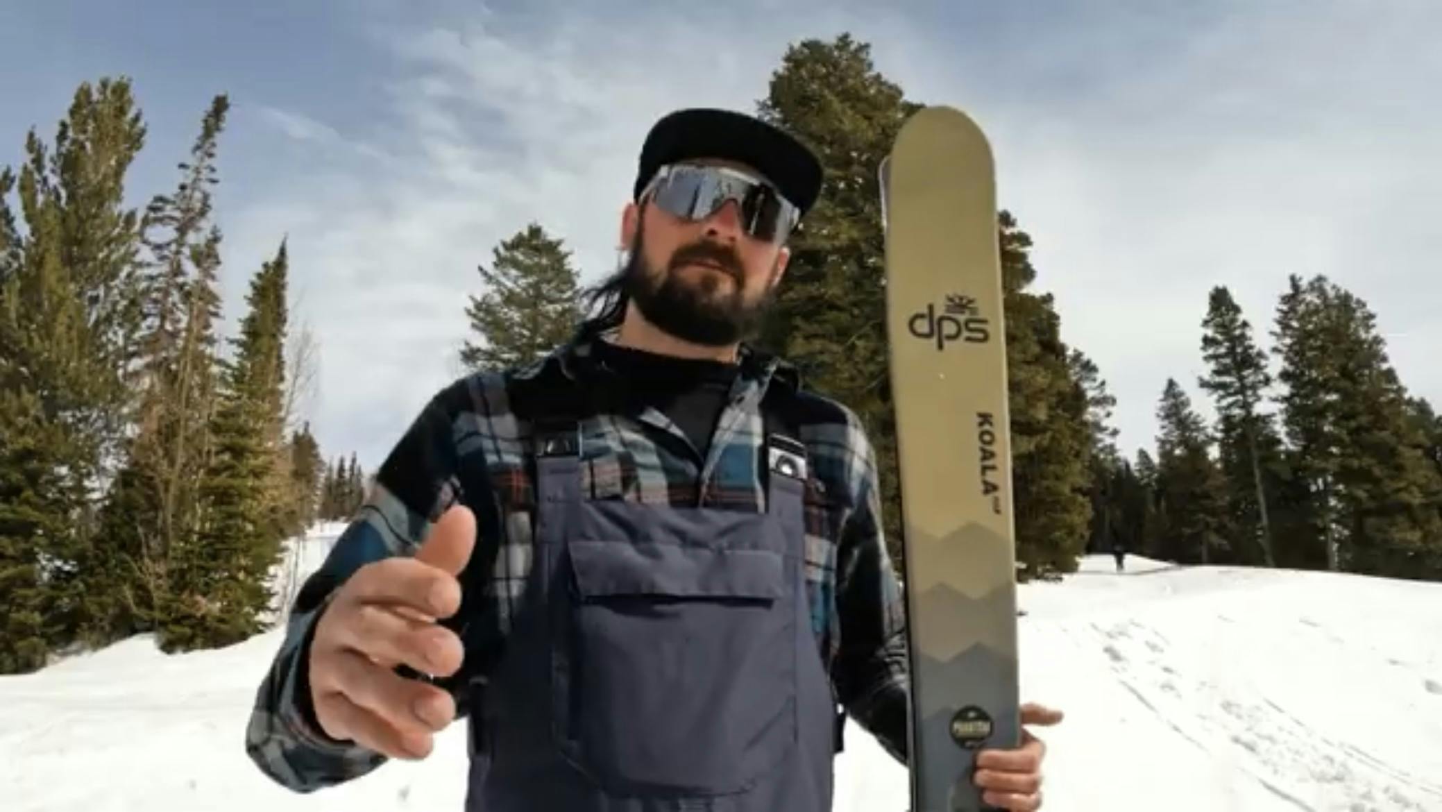 A man at a ski resort holding the DPS Foundation Koala 103 Skis · 2023.