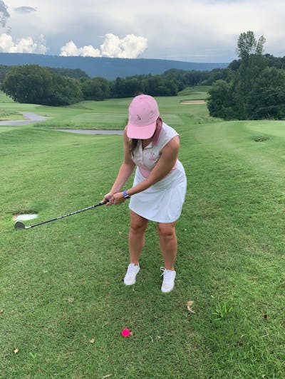 A woman golfing with a club from the Callaway Women's Mavrik Max Combo Set.