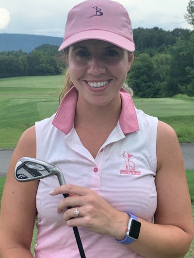 A woman on a golf course smiling with a club from the Callaway Women's Mavrik Max Combo Set.