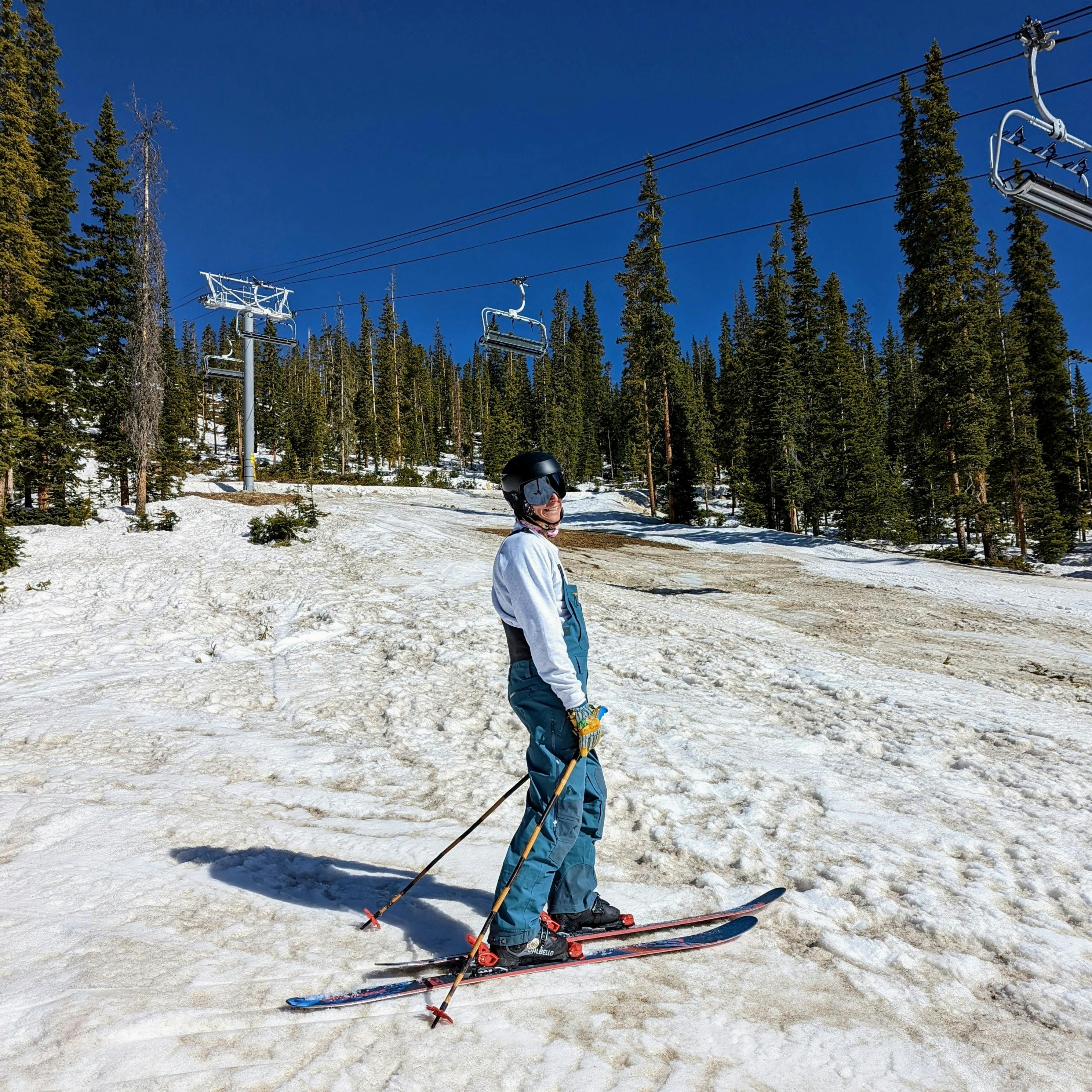 A skier standing under a chairlift on a ski run wearing the Flylow Tough Guy gloves. 
