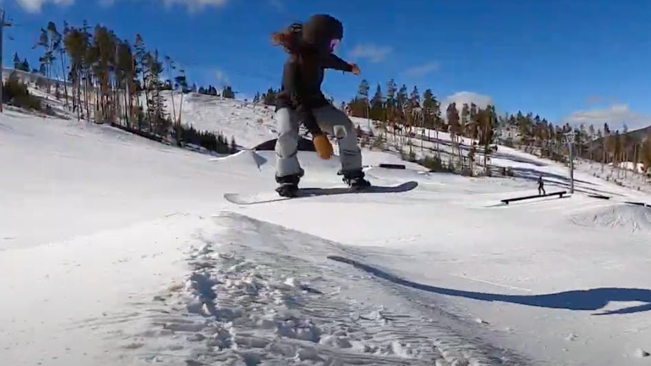 Arielle snowboarding off a jump on a mountain