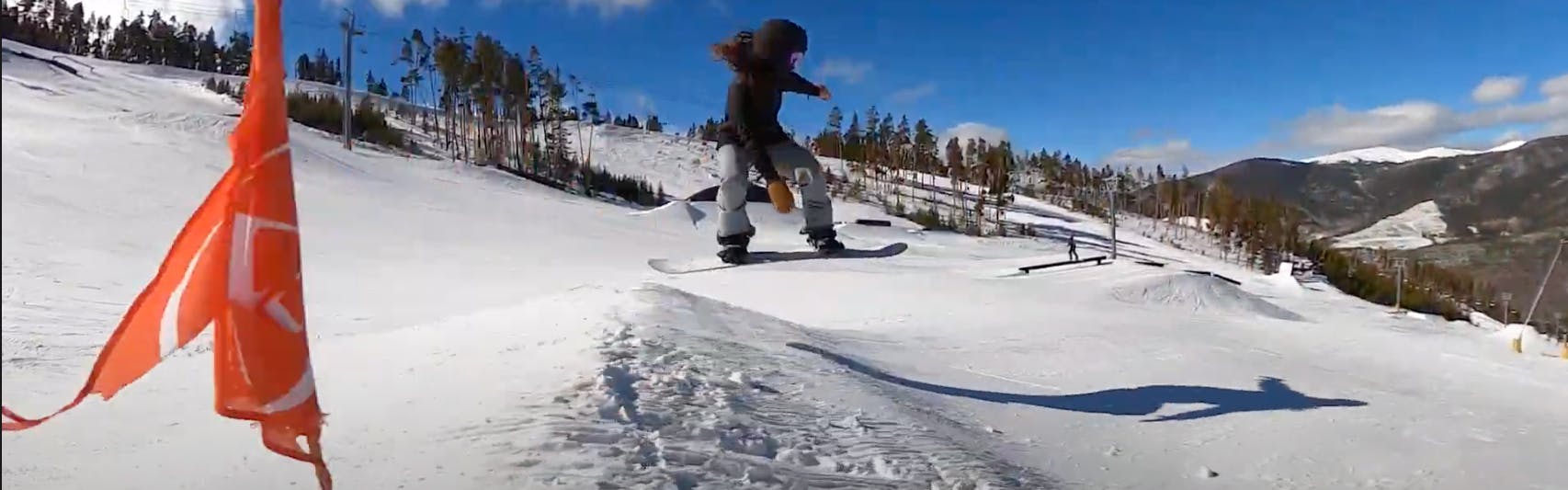Arielle snowboarding off a jump on a mountain