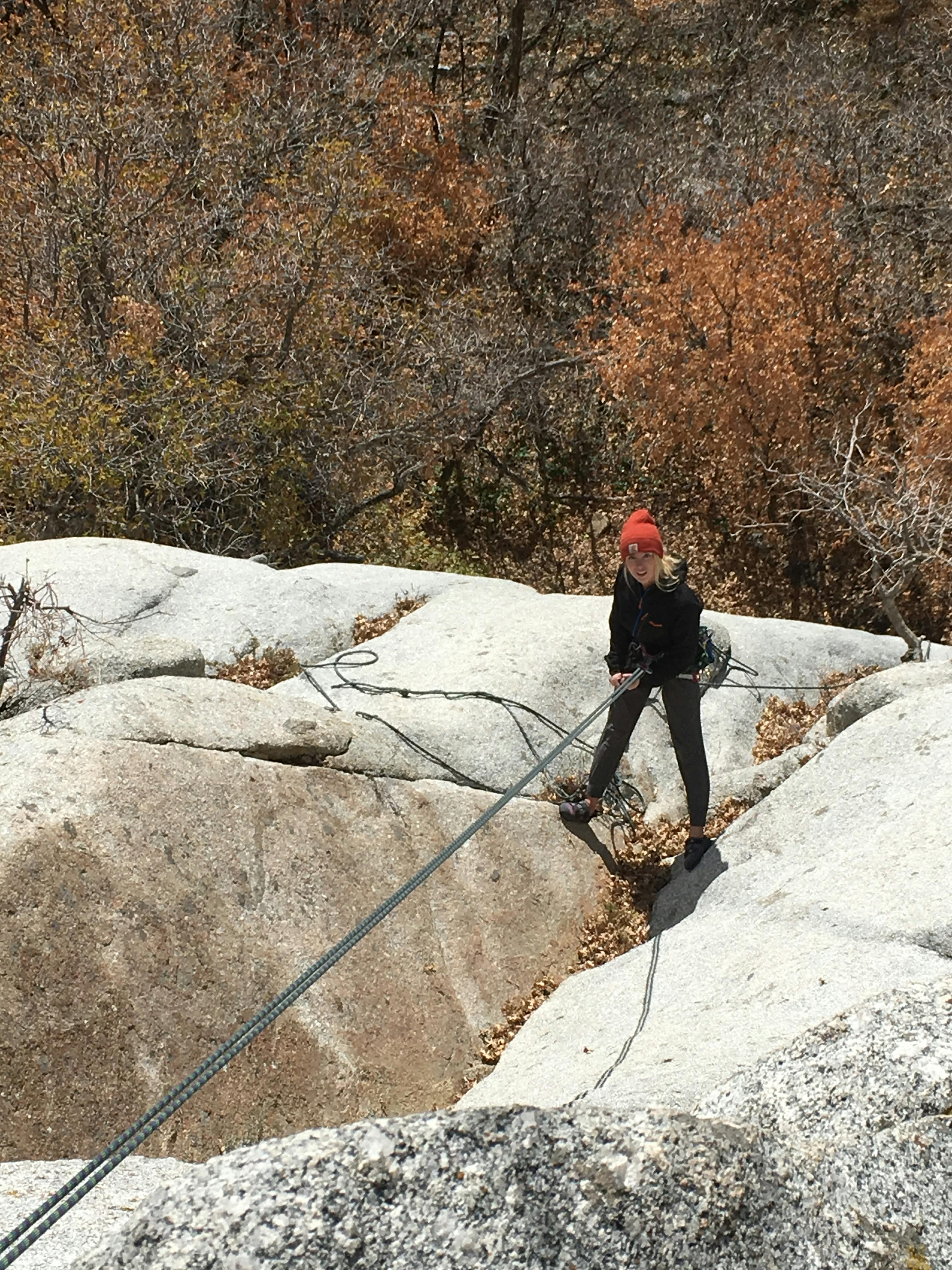 A rock climber on a rope looking up.