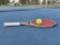 Green tennis racquet with red strings and ball