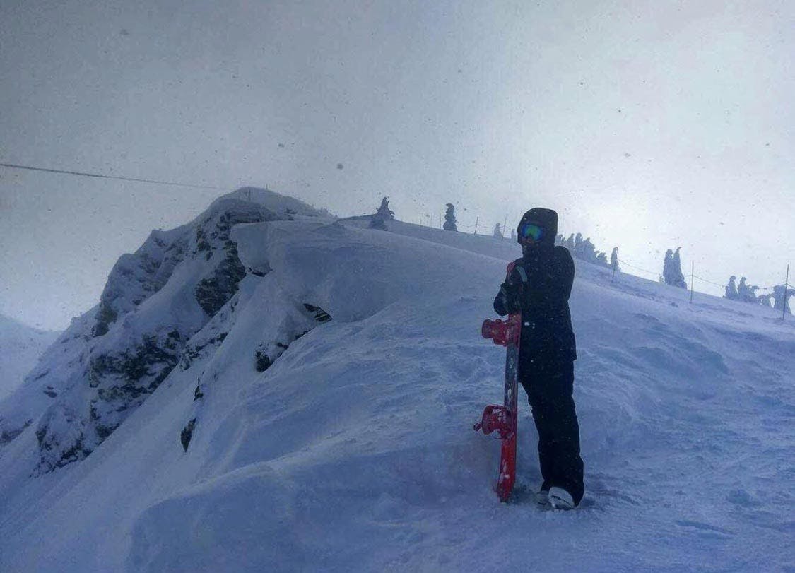 A snowboarder standing at the top of a run with the Salomon Gypsy Snowboard. 