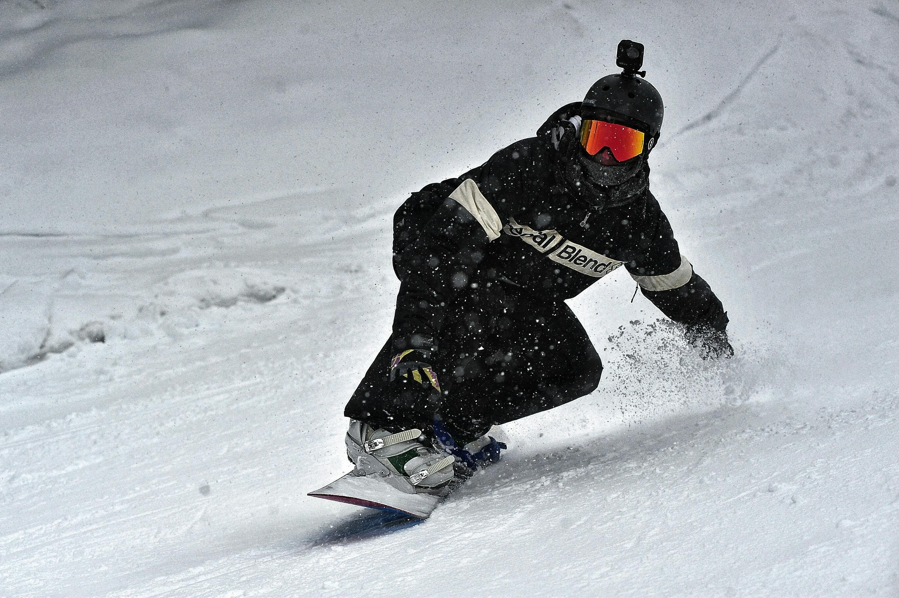 Snowboarder wearing a Go Pro on his helmet shreds down the mountain. 