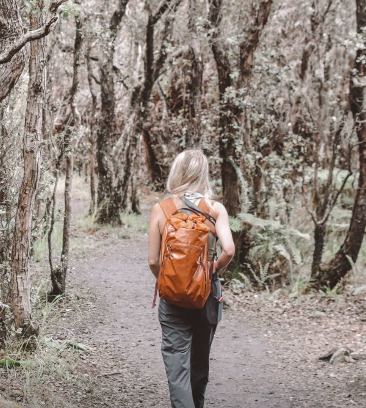 A woman walking down a trail with a backpack on. 