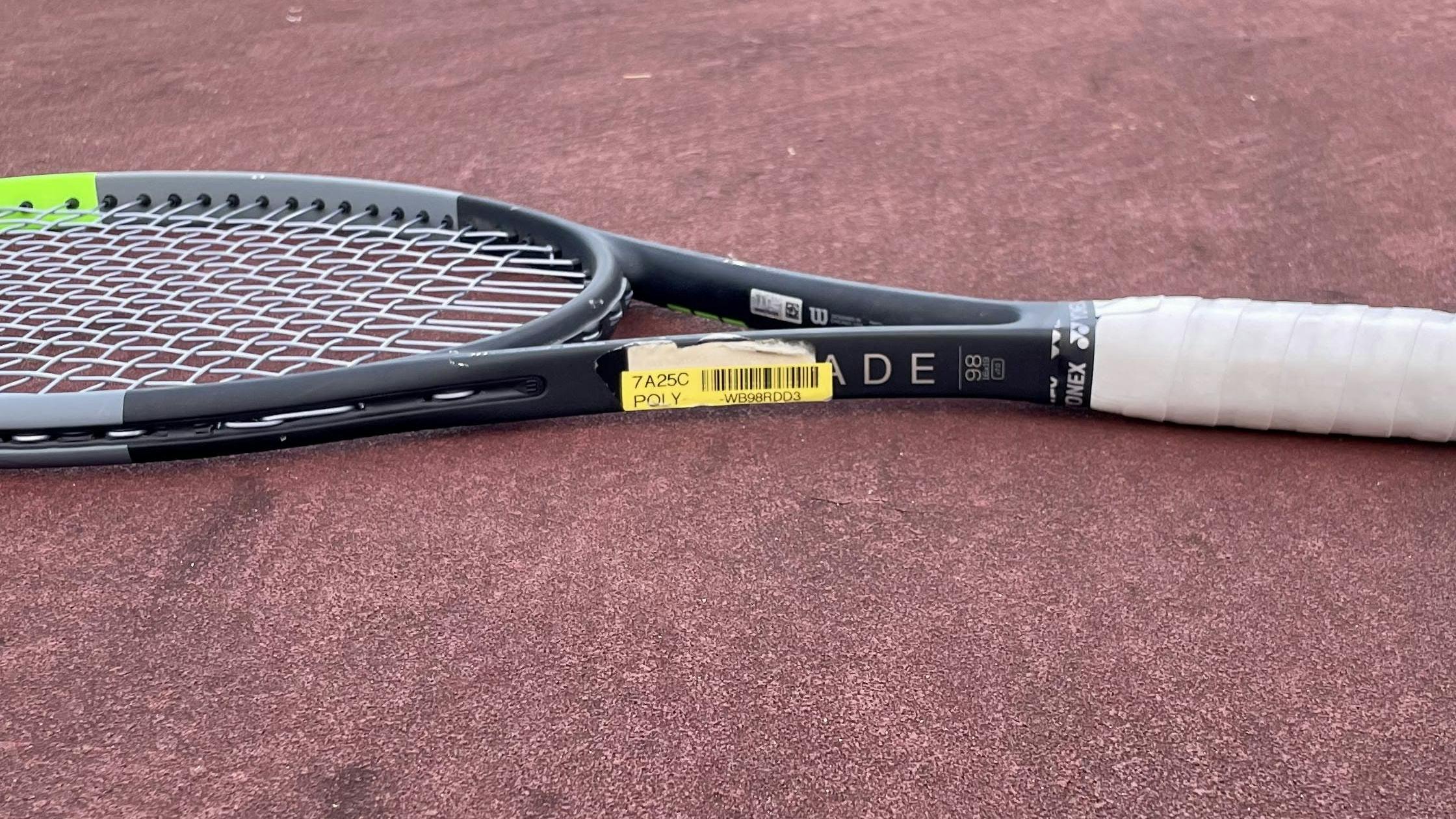 The Wilson Blade 98 V7 Racquet lying on a court. 
