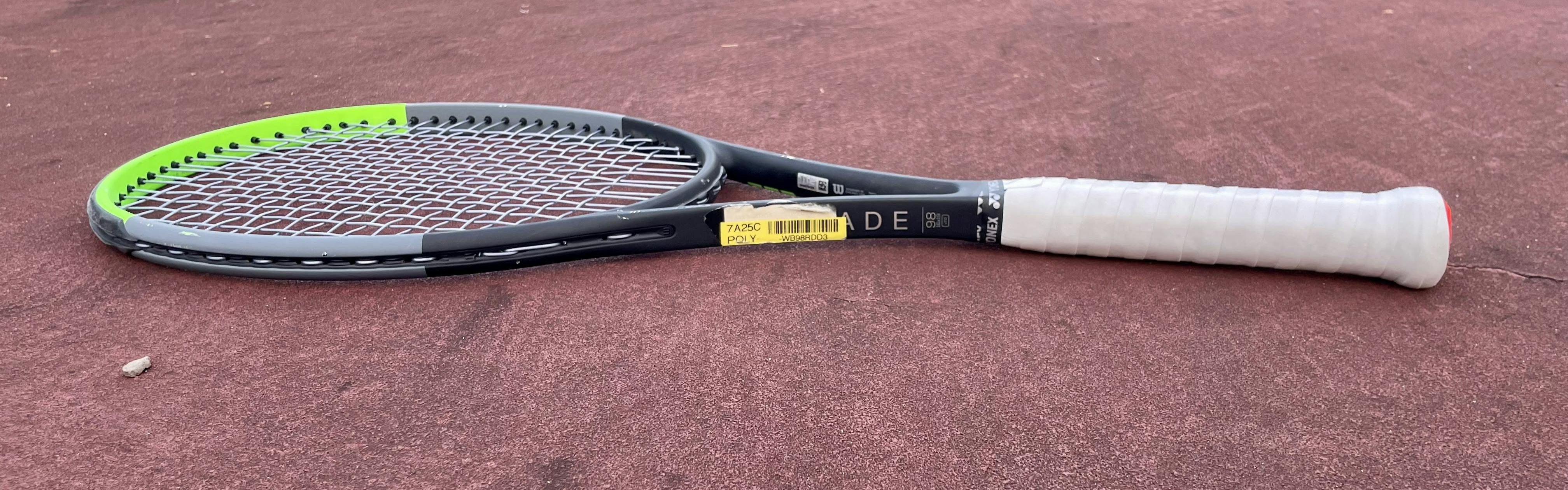The Wilson Blade 98 V7 Racquet lying on a court. 