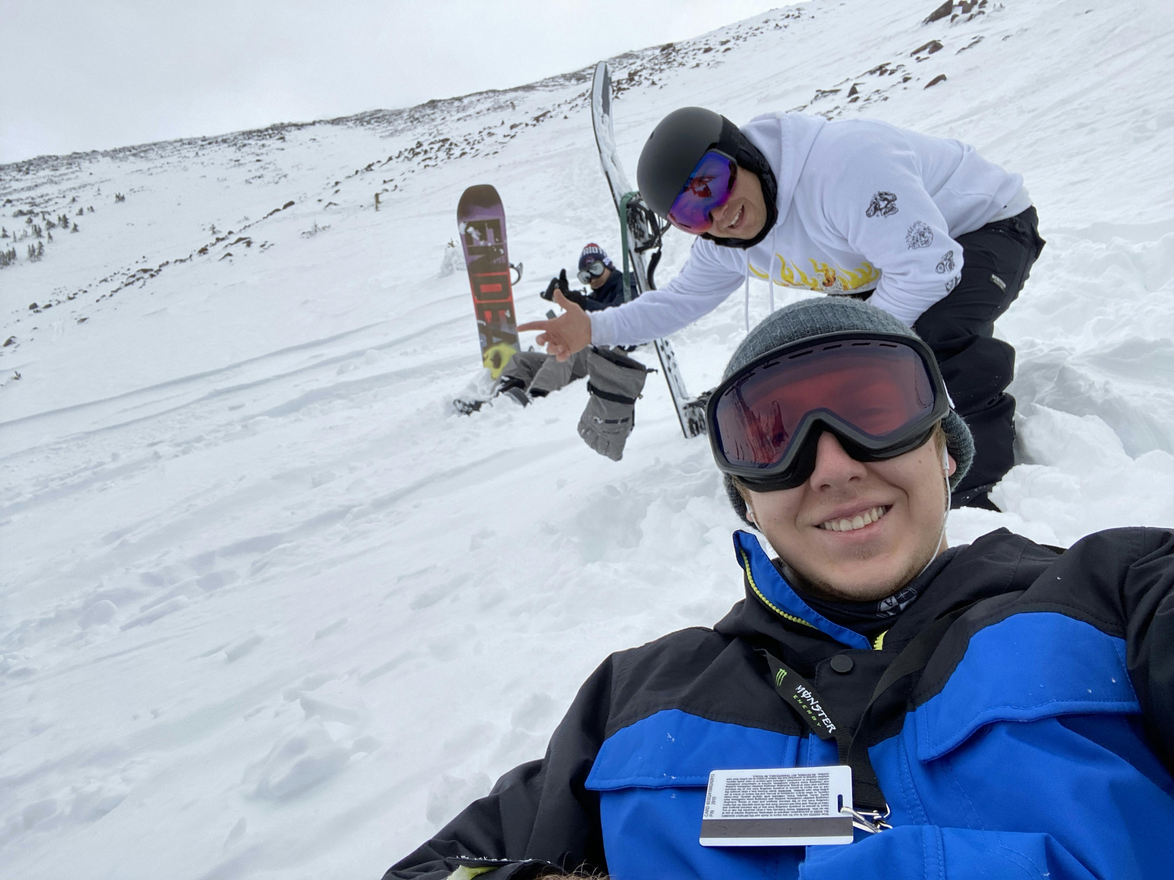 Two snowboarders with a snowy mountain in the background.