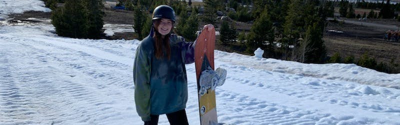 A woman standing in the snow with the Burton Yeasayer Snowboard.
