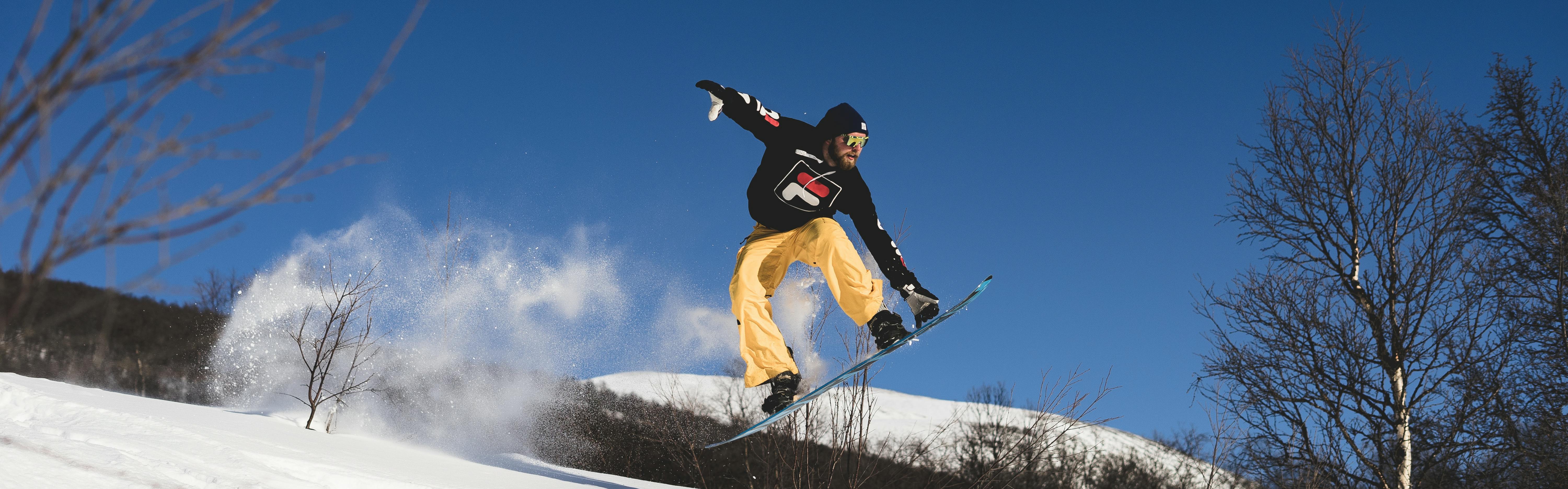 A snowboarder jumping and grabbing his board.