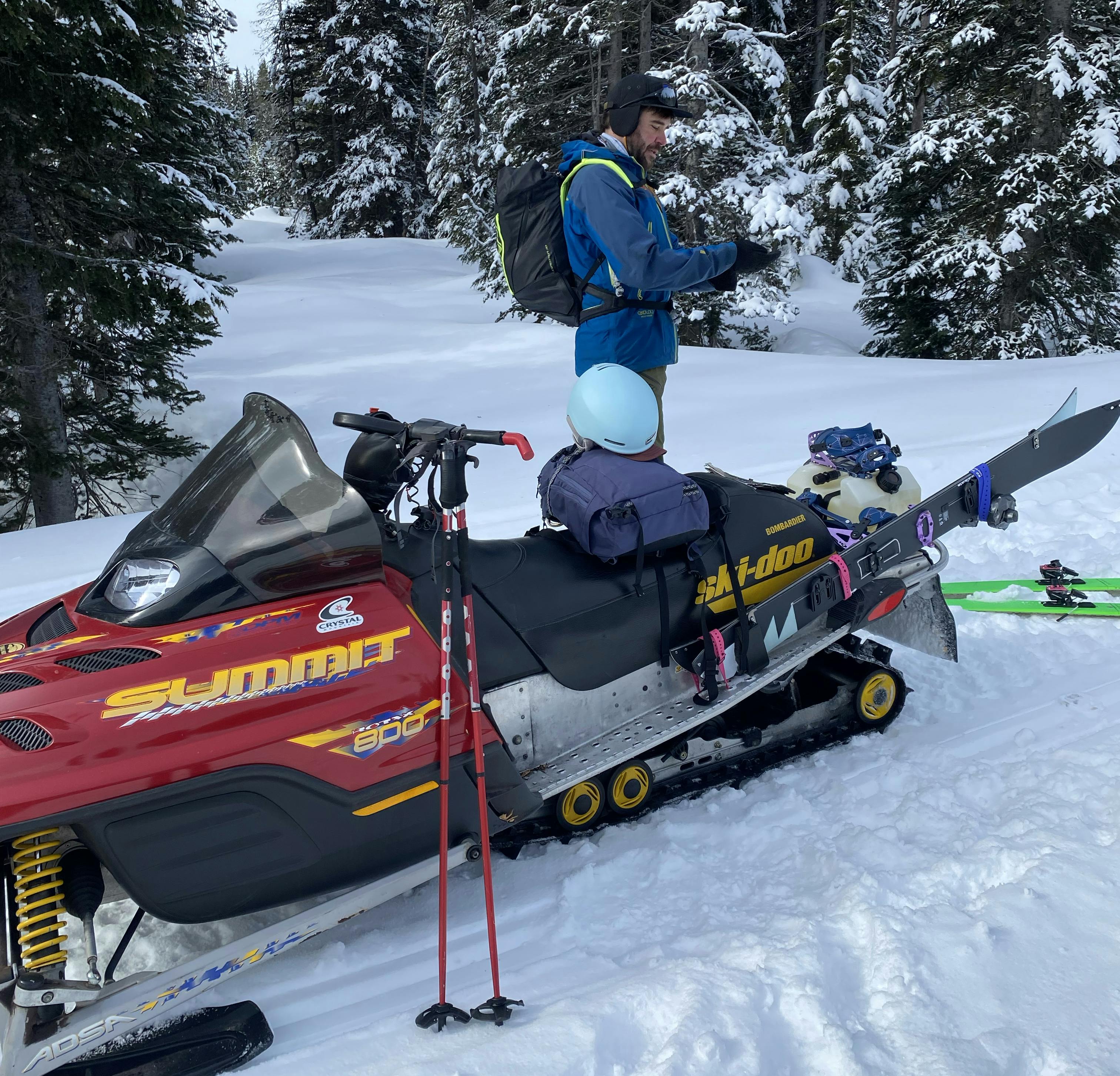 A skier standing next to a snow mobile. 