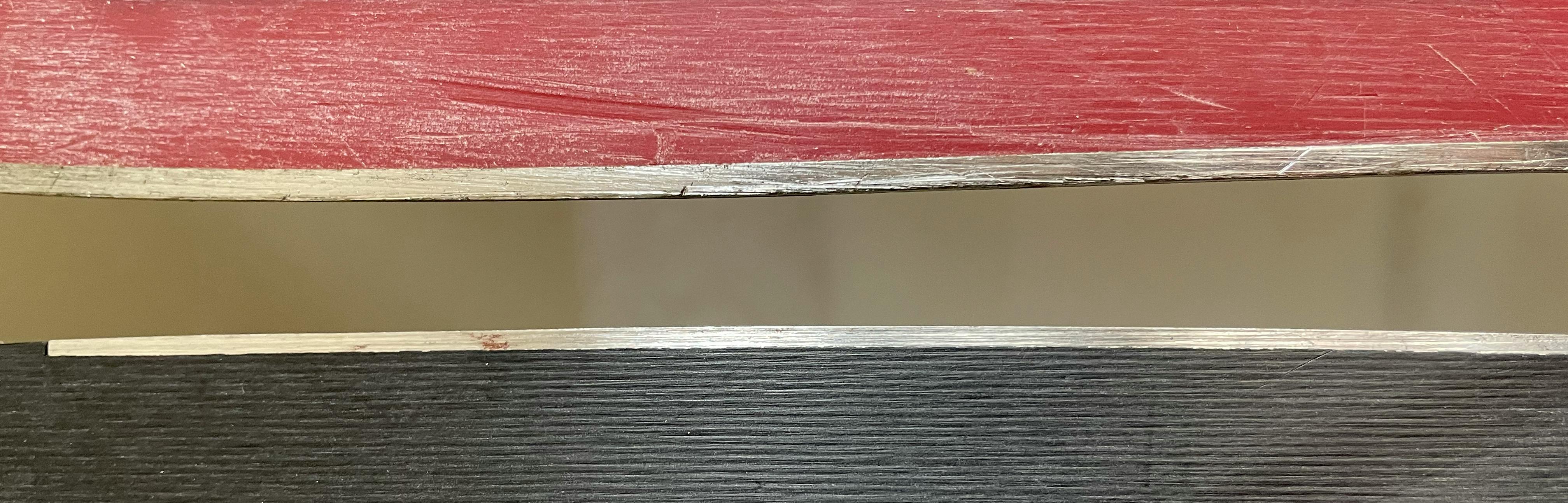 A close-up of two skis and their edge thickness. 