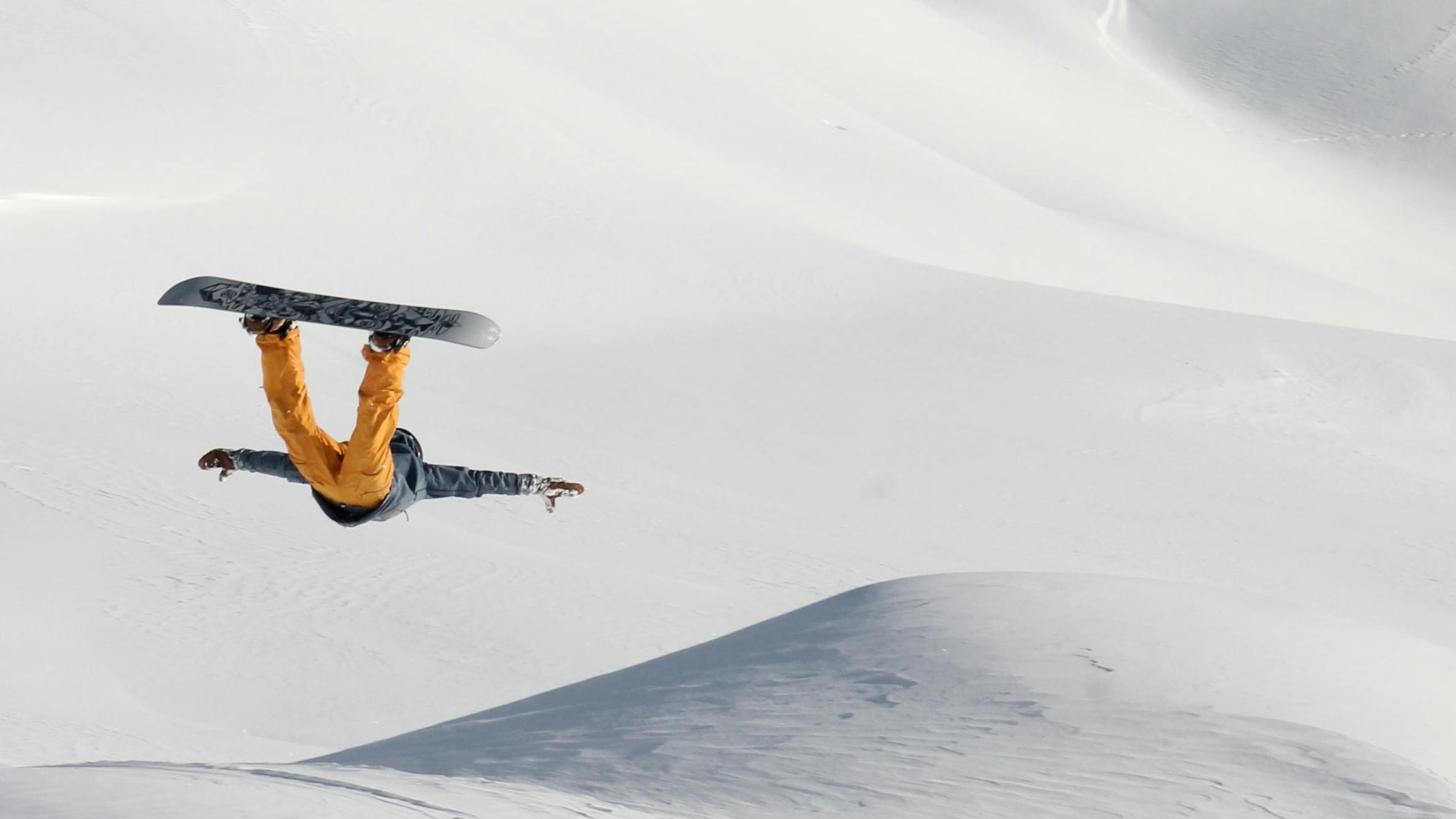 A snowboarder does a flip. 