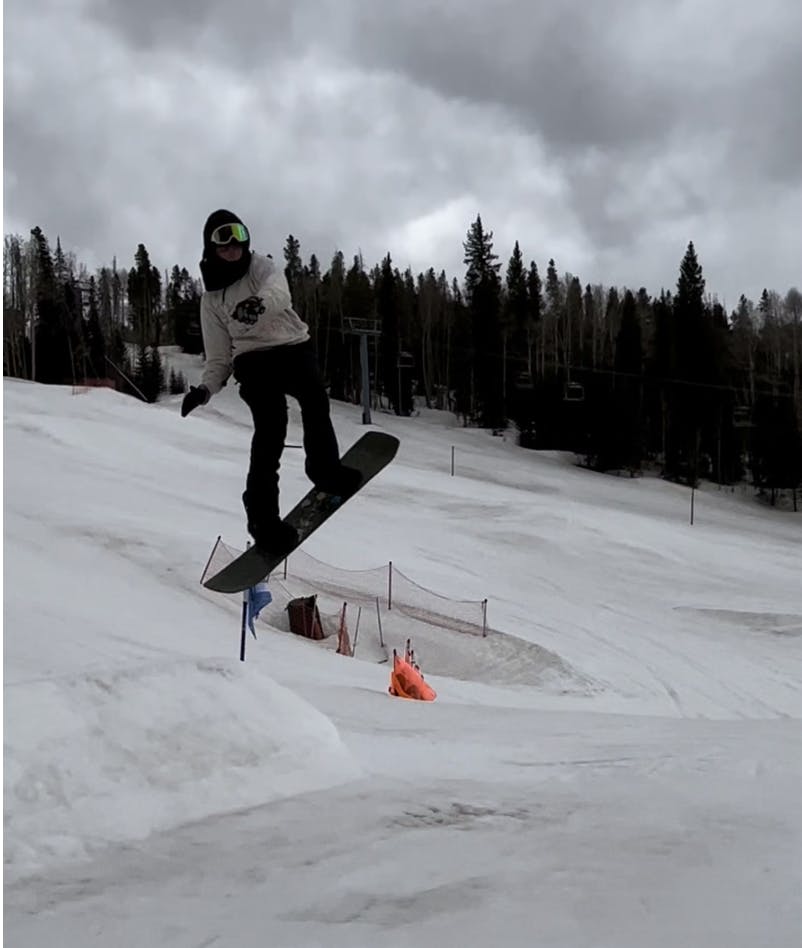 A snowboarder jumping off a jump on the Burton Photon Step On Wide Snowboard Boots.