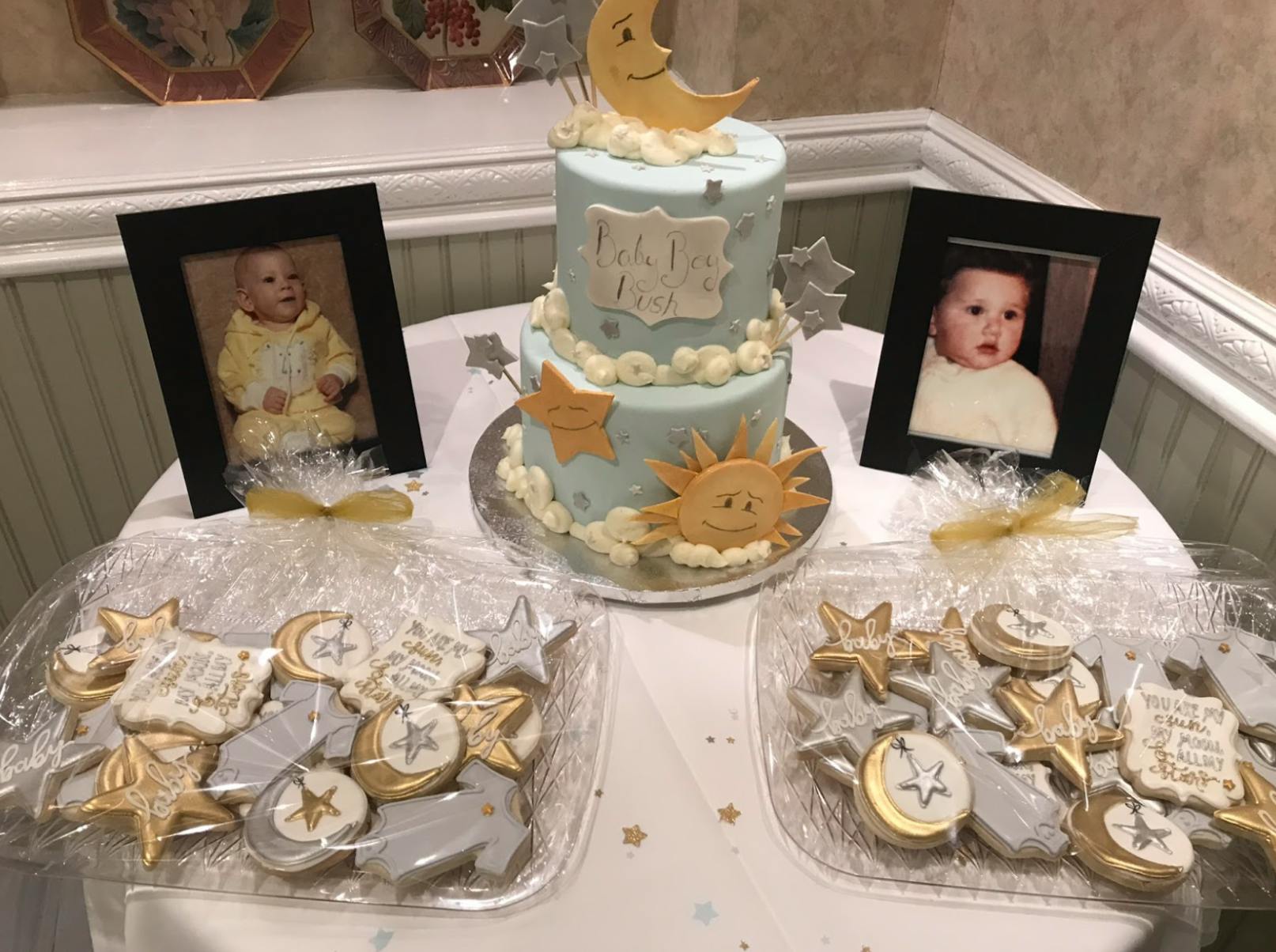 A table with cookies, cake, and photos of babies. 