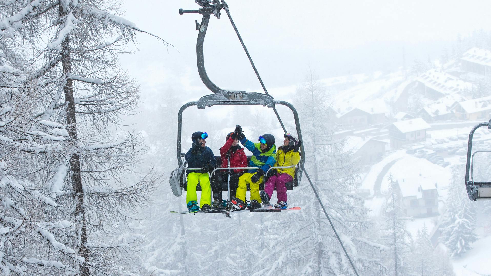 A group of four skiers and snowboarders on a chairlift