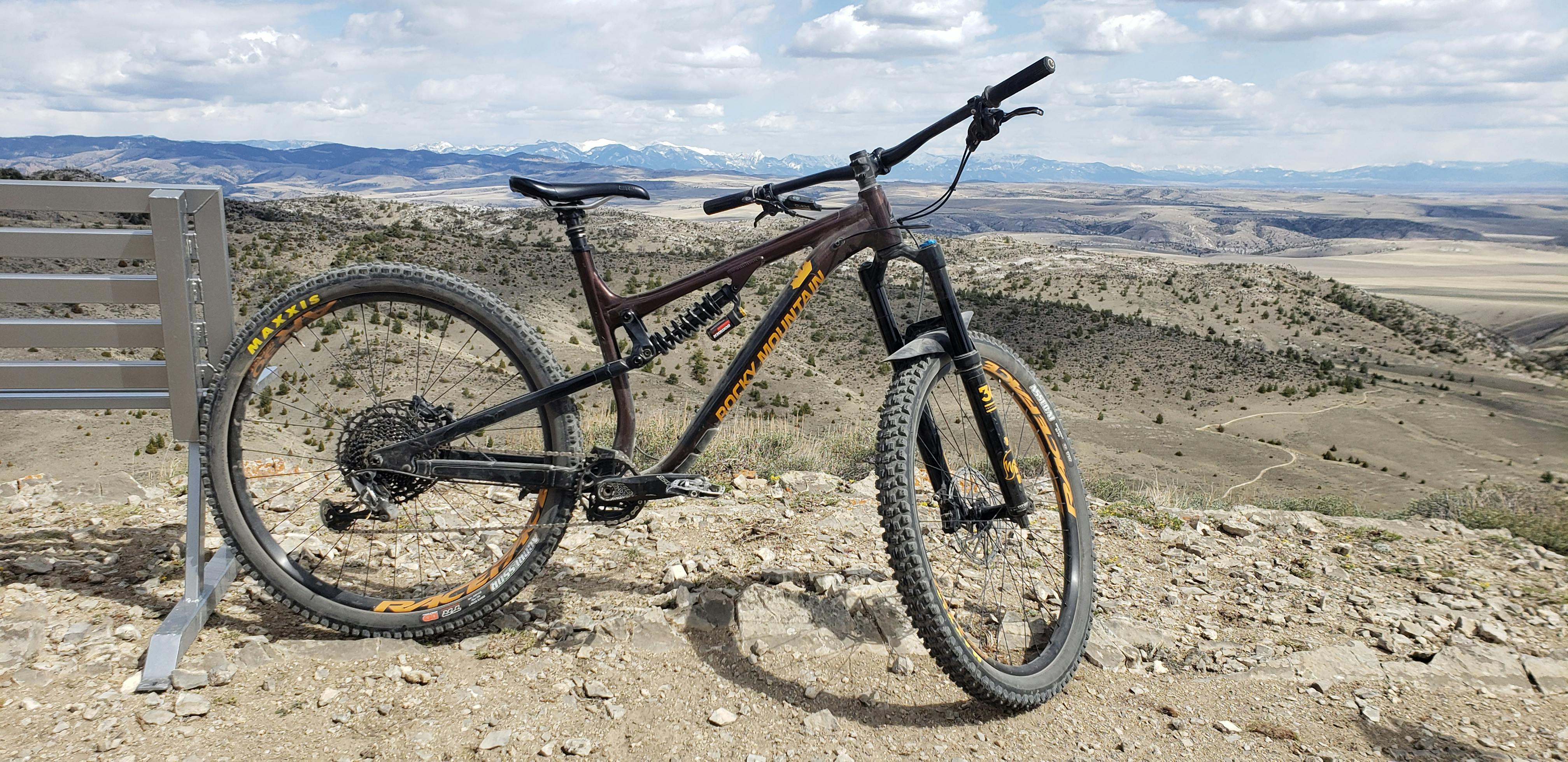 A mountain bike sits on a hill next to a bench