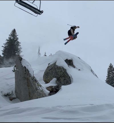 Skier jumps over a snowy rock.