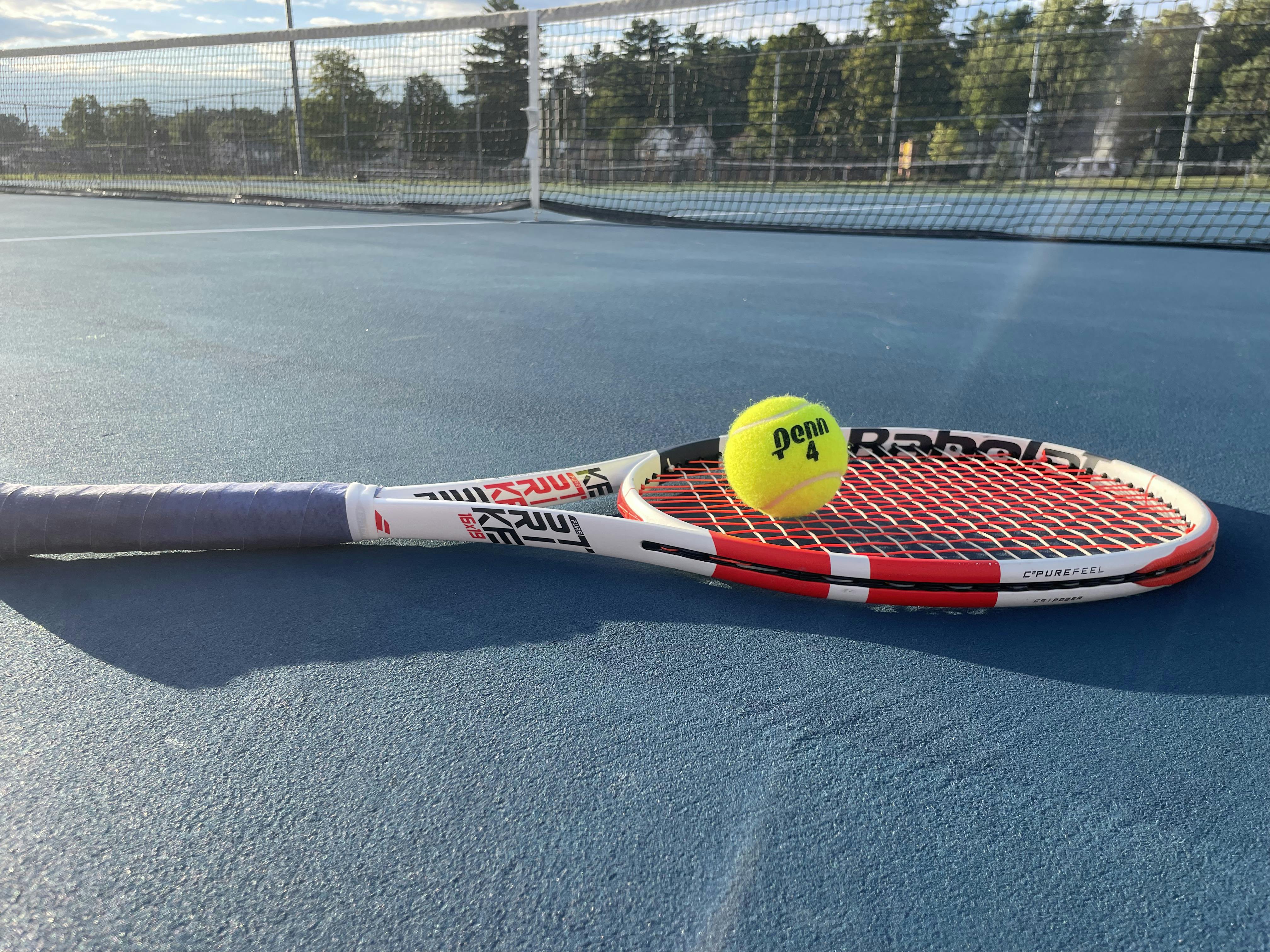 The Babolat Pure Strike 98 16x19 Racquet lying on the tennis court.